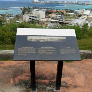 A sign on top of a hill overlooking the ocean.