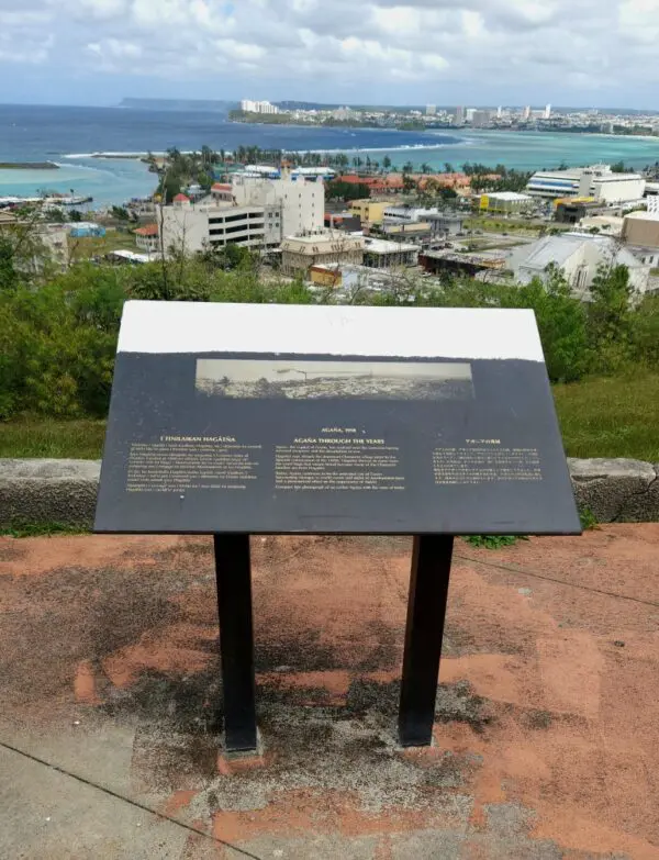 A sign on top of a hill overlooking the ocean.