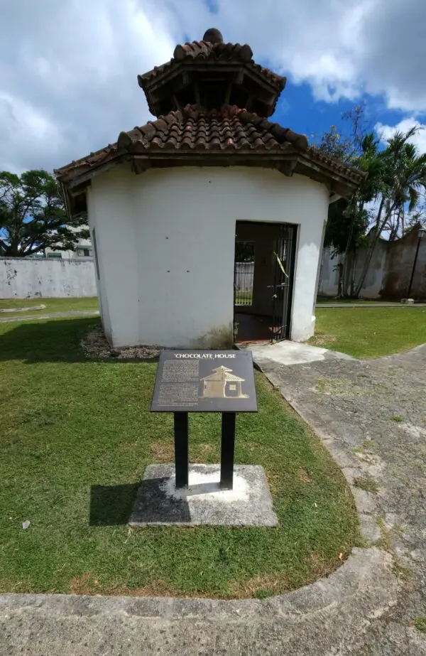 A small white building with a black and silver sign.