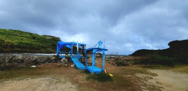 A blue slide in the middle of an open field.