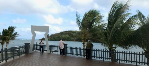 People standing on a deck near the water.