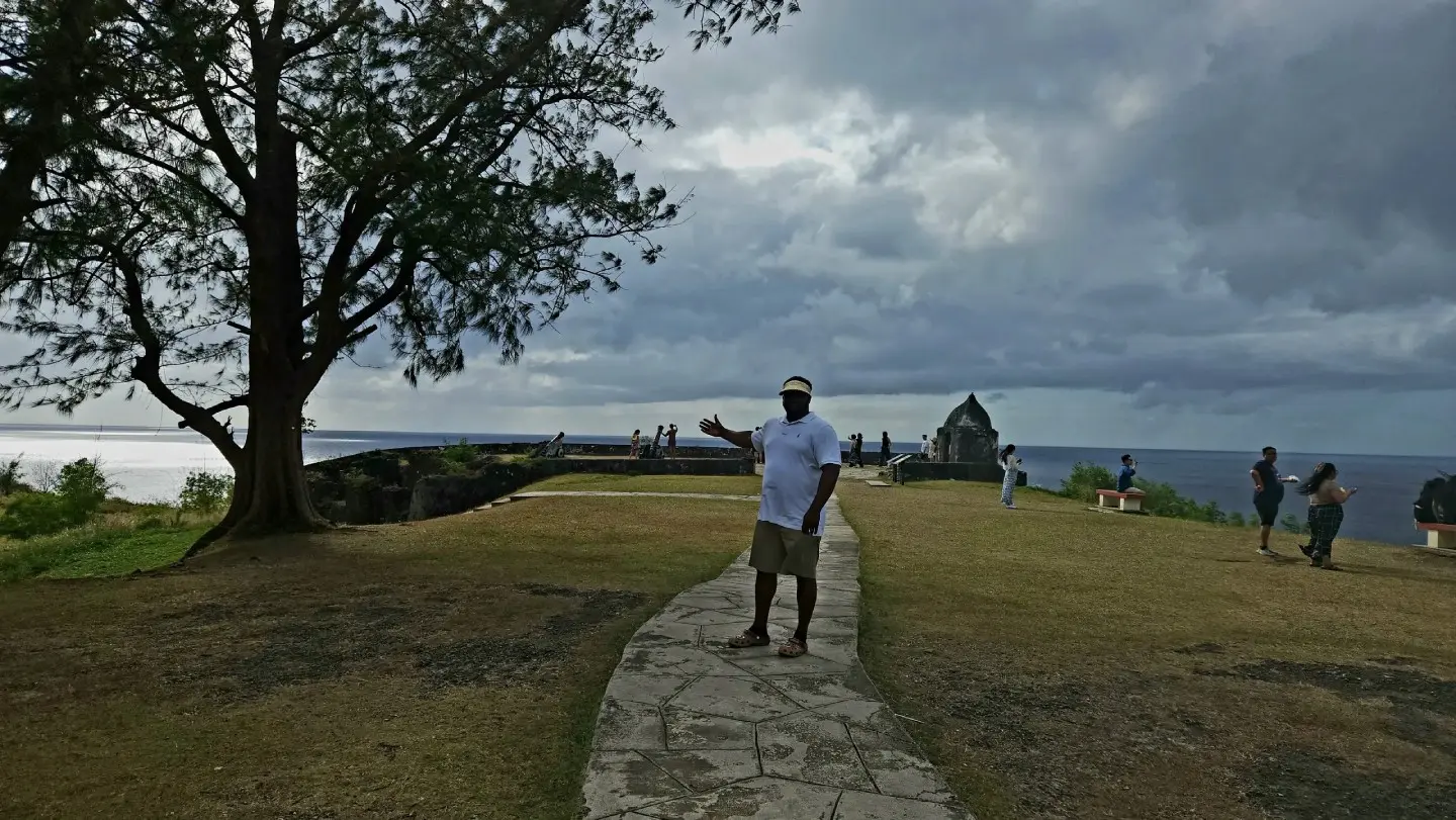 A man standing on the side of a road near water.